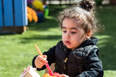 Little girl painting pumpkin